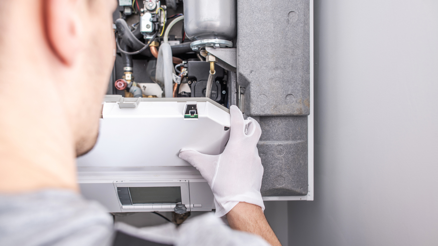 A man in white gloves is fixing a water heater