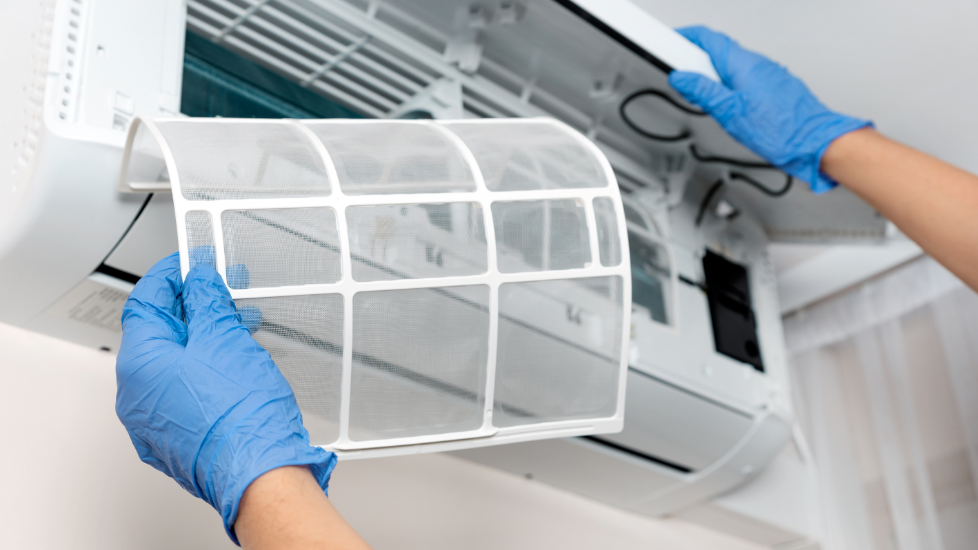 A person in blue gloves and blue gloves cleaning a white air conditioner